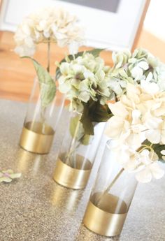 three vases with flowers in them sitting on a counter top next to each other