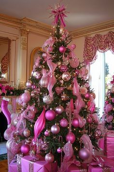 Christmas tree decorated with pink ornaments and ribbons in an elegantly furnished room. Pink Tree Aesthetic Christmas, Christmas Tree Ideas Pink, Pink Themed Christmas Tree, Pink Ornament For The Tree, Little Pink Christmas Tree Girl Rooms