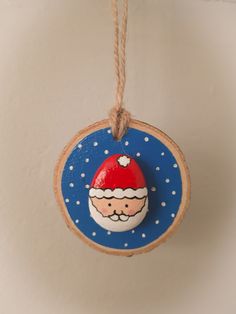 a wooden ornament with a santa clause face on it hanging from a rope