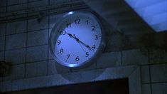 a clock on the side of a building lit up with blue light at night time