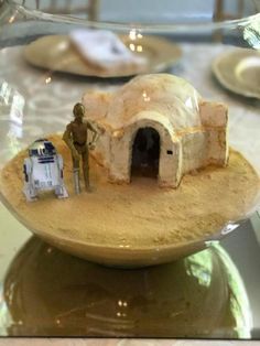 a star wars scene is displayed in a glass bowl on a table with plates and utensils