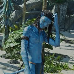 a man with blue paint on his face and body is standing in front of palm trees