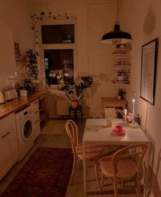 a kitchen with a table, chairs and a washing machine in the middle of it