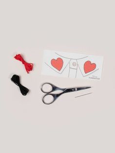 scissors, thread, and sewing supplies laid out on a white surface with a piece of paper in the background