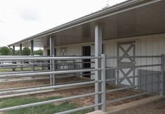 the inside of a building with metal railings and horses in pens on either side