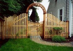 a wooden gate in front of a house with a brick walkway leading up to it