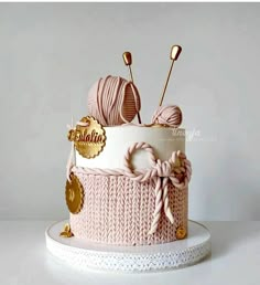 there is a pink cake decorated with knitting needles and balls of yarn on the top