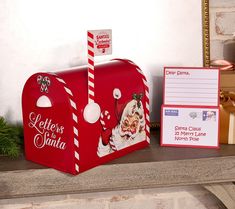 a red mailbox sitting on top of a mantle next to a christmas card holder