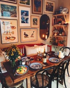 a dining room table with plates and bowls on it, surrounded by many framed pictures