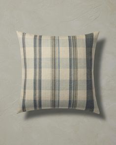 a gray and white plaid pillow sitting on top of a wall