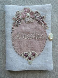 a small embroidered piece on top of a white cloth with pink flowers and the word mean written in cursive writing