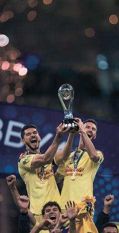 two soccer players are holding up the trophy