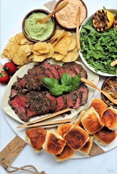 a platter filled with meat, chips and vegetables next to dips on skewers