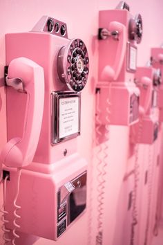 pink telephones are lined up on the wall