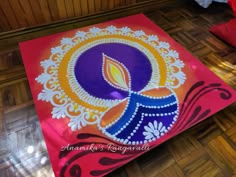 a colorful painting on the floor with a candle in it's center and some decorations around it