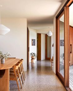 a dining room table with chairs and vases on top of it next to an open door