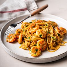 a white plate topped with pasta and shrimp