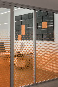 an office cubicle with orange and black dots covering the walls, along with a laptop on a desk