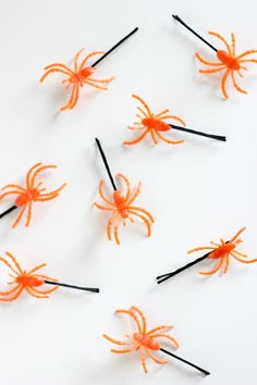 several orange plastic spider wands with black sticks sticking out of them on a white surface