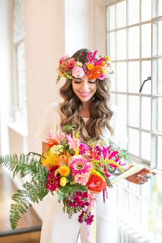 a woman with flowers in her hair holding a bouquet