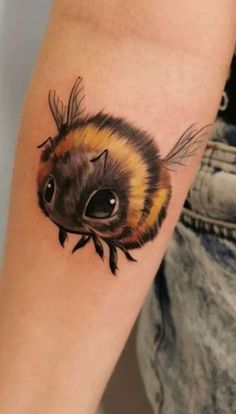 a close up of a person's arm with a bee tattoo on the wrist