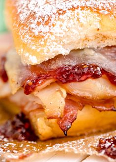 a close up of a sandwich on a plate with powdered sugar and cranberry sauce