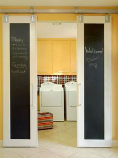 an open door to a laundry room with chalk writing on the wall and washer dryers