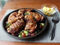 a plate full of chicken and vegetables next to a bowl of potatoes on a table