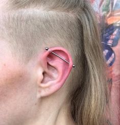 a woman with an ear piercing in front of her face and behind her ear is a piece of metal