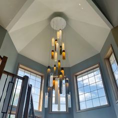 a chandelier hanging from the ceiling in a room with three windows and two staircases