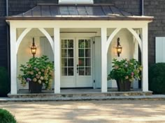 two potted plants on the front porch of a house with white trim and columns