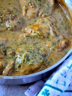 a pan filled with meat and gravy on top of a blue table cloth