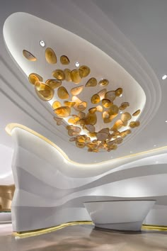 an artisticly designed lobby with white walls and gold accents on the ceiling is lit by recessed lights