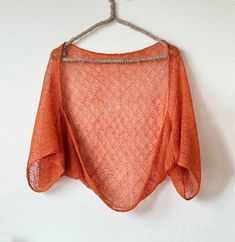 an orange top hanging on a white wall