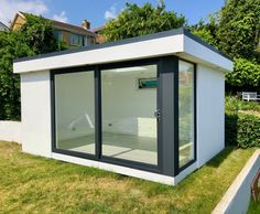 a small white and gray building sitting in the grass