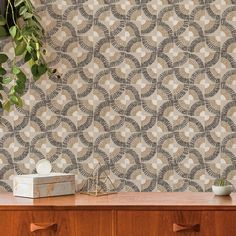 a wooden dresser with a plant on top of it and a wall paper behind it