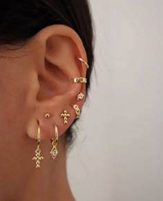 a woman wearing an ear cuff with cross and arrow designs on it's side