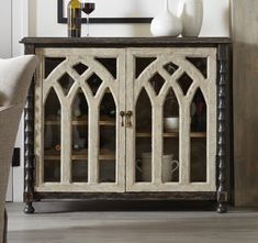 an old wooden cabinet with glass doors and arched windows on the front, sitting in a living room