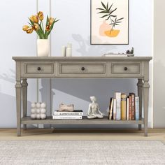 a gray console table with two drawers and some books on it in front of a white wall