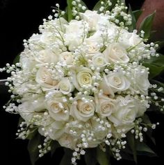 a bridal bouquet with white roses and baby's breath in the center is being held by someone