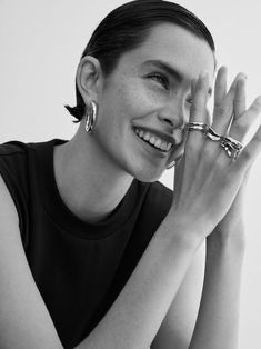 black and white photograph of a woman smiling with her hands on her face while holding two rings