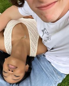 a man and woman laying on the ground with their arms around each other's head