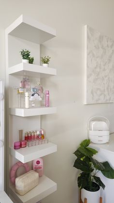 a white shelf filled with lots of beauty products and plants next to a potted plant