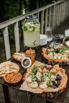 a wooden table topped with lots of food next to a jar filled with drinks and snacks