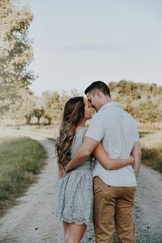 a man and woman kissing on the side of a dirt road