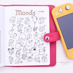 an open notebook with doodles on it next to a cell phone