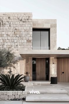 the front entrance to a modern house with stone walls and steps leading up to it