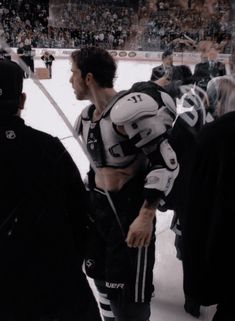 a hockey player standing on the ice talking to his team mates in front of an audience