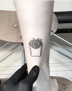 a person with a small tattoo on their leg that has french fries in a cup