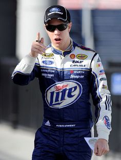 a man in a racing suit pointing to something